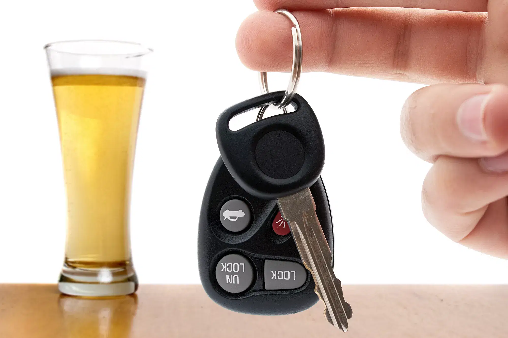 A person demonstrating responsible beverage service by holding a car key next to a glass of beer during online training for alcohol safety.